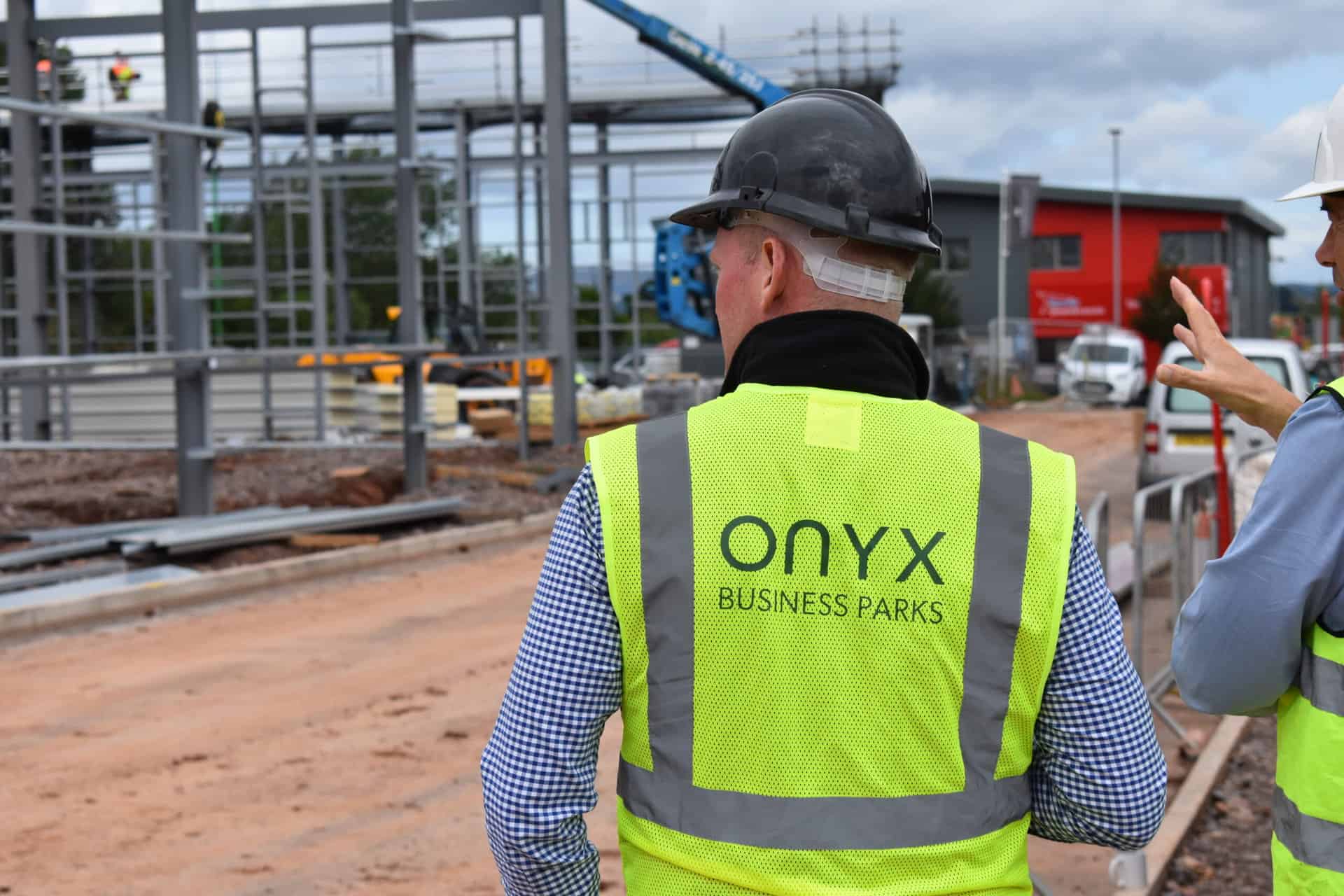 Onyx team member at the West Park, Wellington construction site, wearing a high-visibility vest featuring 'Onyx.' The site showcases progress with steel beams in place, signalling the advancement of the development phase.