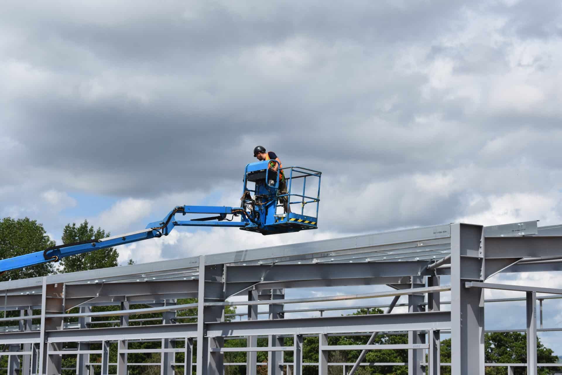 Contractor at West Park, Wellington, operating a boom lift to reach the upper levels of a steel frame structure during the construction phase.