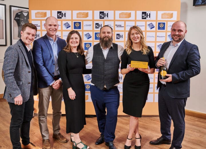 6 people standing together holding a prize