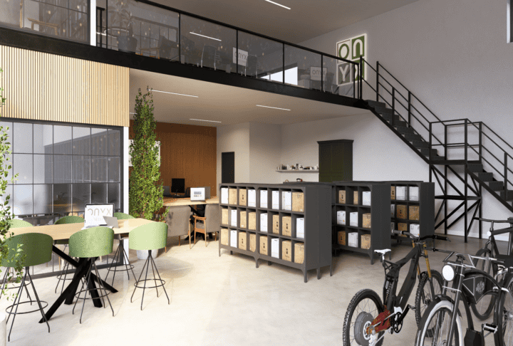 Buying a Commercial Workspace? Here's an example of a contemporary bike sales office featuring a ground floor layout with shelving units, bicycles on display, and workstations. The space includes green chairs around a table and plants adding a touch of greenery, with a staircase leading to the mezzanine.