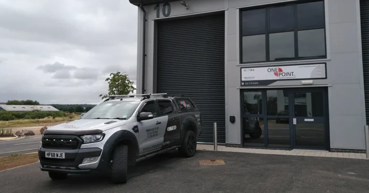 One Point Survey Equipments office at SkyPark, Exeter. A company car is parked in front of their light industrial unit.