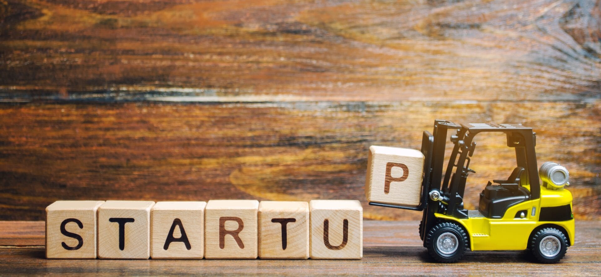 A row of wooden blocks with the letters for the word "startup" being put into place by a toy forklift. Indicating How Startups Thrive at Onyx Business Parks.